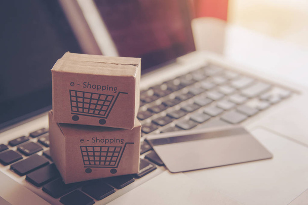 Shopping online concept - Shopping service on The online web. with payment by credit card and offers home delivery. parcel or Paper cartons with a shopping cart logo on a laptop keyboard - Foto, Bild