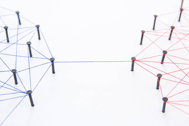 Концепція з'єднання мереж - дві мережі, пов'язані з пряжею червоного та синього кольорів на білому папері. Симулятор з'єднання соціальних мереж, Інтернету, комунікації людей
 - Фото, зображення