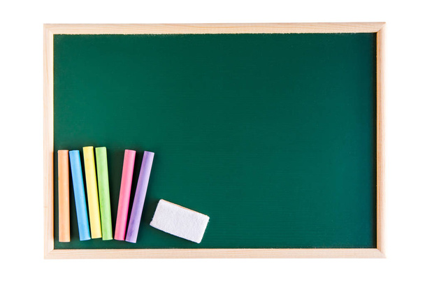 Gekleurde krijt en leeg schoolbord gum op lege groen bord geïsoleerd op een witte achtergrond. met kopie ruimte voor tekst toevoegen - Foto, afbeelding