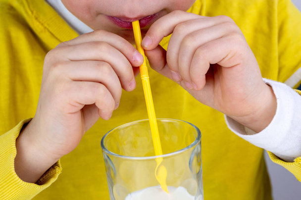 Cute boy drinks milk using a drinking straw - Foto, imagen