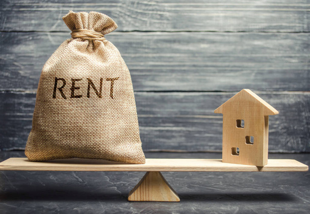Money bag with the word Rent and a wooden house on the scales. The concept of payment for rental housing. Debt repayment. To renting a house. Rent a property. Court, Law and Justice - Foto, immagini