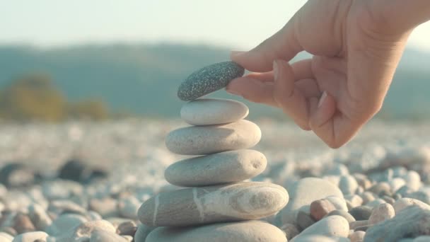 Stone evenwicht close-up. Vrouwelijke hand maken kiezels toren uit zee stenen - Video