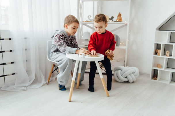 two brothers play puzzle on the table in the childrens room in the Scandinavian style - Zdjęcie, obraz