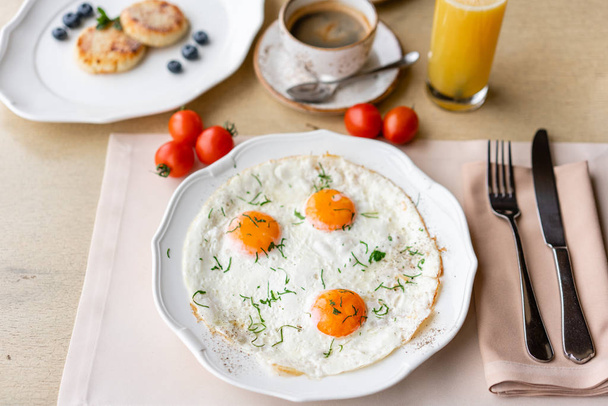 Huevo frito. Vista de cerca del huevo frito en un plato blanco. Desayuno ligero por la mañana, pasteles calientes frescos y café capuchino aromático
 - Foto, imagen