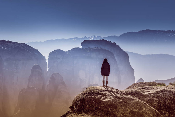 Nainen seisoo kivellä Meteorassa Kreikassa katsomassa näkymää
. - Valokuva, kuva