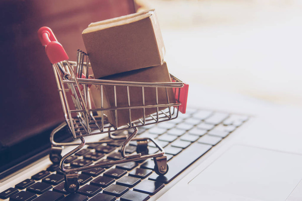 Online kavramı alışveriş - online web üzerinde hizmet alışveriş. evlere servis sunmaktadır. bir dizüstü bilgisayar klavye logosuna parsel veya kağıt karton bir alışveriş sepeti - Fotoğraf, Görsel