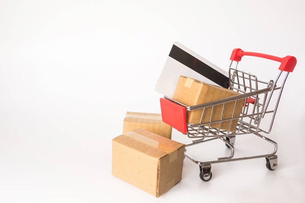 Einkaufskonzept: Kartons oder Papierschachteln und Kreditkarte in rotem Warenkorb auf weißem Hintergrund. Online-Shopping Verbraucher können von zu Hause und Lieferservice einkaufen. mit Kopierraum - Foto, Bild