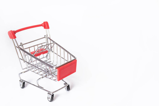 Carrinho de compras vermelho ou carrinho de supermercado no fundo branco com espaço de cópia
 - Foto, Imagem