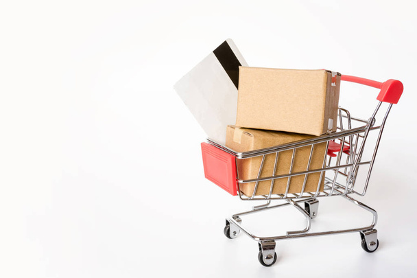 Vásárlás koncepció: karton vagy papír dobozok és hitel kártya, bevásárló kosár, a piros fehér háttér. online vásárlás-fogyasztók vásárolhatnak a hazai és a szállítási szolgáltatás. a hely másolás - Fotó, kép
