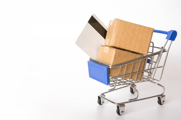 Einkaufskonzept: Kartons oder Papierschachteln und Kreditkarte in blauem Warenkorb auf weißem Hintergrund. Online-Shopping Verbraucher können von zu Hause und Lieferservice einkaufen. mit Kopierraum - Foto, Bild