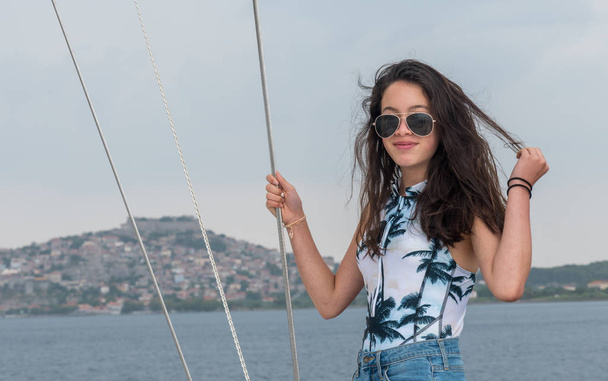 Young teen girl with sunglasses on deck of sailboat in bathing suit - Photo, Image