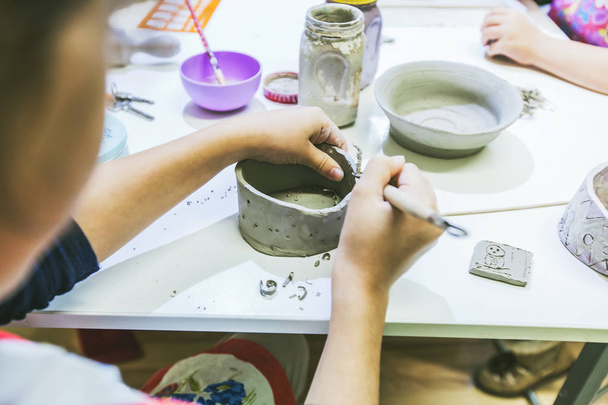 陶芸教室で土の花瓶に取り組む子供アーティスト. - 写真・画像