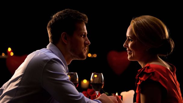 Casal de mãos dadas e admirando uns aos outros na data romântica no restaurante
 - Foto, Imagem