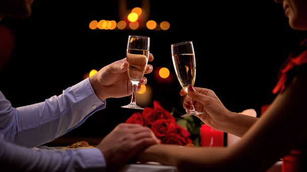 Pareja sosteniendo copas con champán, hombre acariciando mano dama tiernamente, romance
 - Foto, Imagen