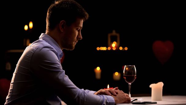 Unhappy man sitting alone in restaurant, waiting for woman, unsuccessful date - Foto, immagini
