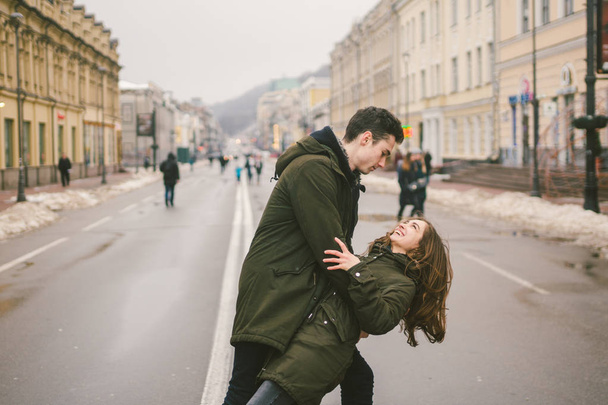 Theme love and romance. Caucasian young people heterosexual couple in love students boyfriend girl hugging and kissing on center of road in center of European city. Man woman happiness love and youth. - Φωτογραφία, εικόνα