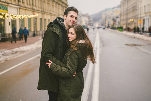 Theme love and romance. Caucasian young people heterosexual couple in love students boyfriend girl hugging and kissing on center of road in center of European city. Man woman happiness love and youth. - Φωτογραφία, εικόνα