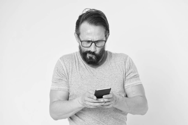 Guy silmälasit ymmällään kasvot käyttävät älypuhelinta. Mies käyttäjä vuorovaikutuksessa sovelluksen älypuhelin. Guy parrakas kypsä vuorovaikutuksessa mobiili käyttöliittymä sovellus. Vaikea tottua digitaalinen gadget aikuisille - Valokuva, kuva