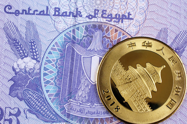 A close up image of a shiny Chinese gold coin with an Egyptian twenty five piastre bank note - Photo, Image