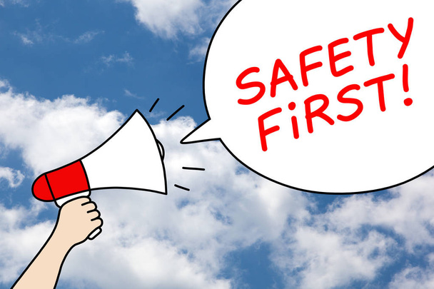 Drawing of a hand holding a megaphone with text Safety First in a speech bubble on blue sky and clouds background.  - Foto, Imagem
