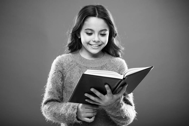 Useful information for her. Girl hold book read story over orange background. Child enjoy reading book. Book store concept. Wonderful free childrens books available to read. Childrens literature - Foto, imagen