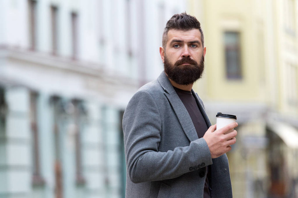 One more sip of coffee. City lifestyle. Businessman well groomed appearance enjoy coffee break out of business center urban background. Relax and recharge. Man bearded hipster drink coffee paper cup - Photo, Image
