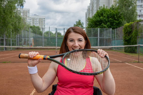 Fogyatékkal élő fiatal nő a kerekesszékes tenisz játék tenisz pálya. - Fotó, kép