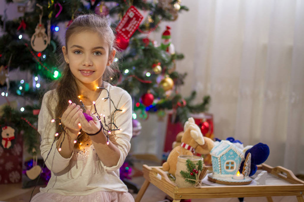 Sweet girl holding lights over Christmas decoration  - Photo, Image