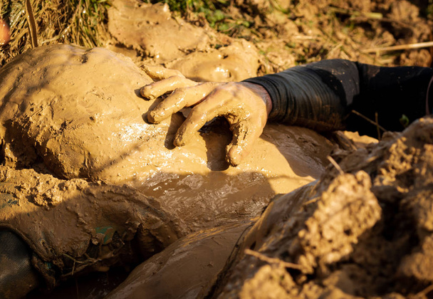 アクションで泥だらけの障害物競走のランナー。泥を実行します。手の詳細. - 写真・画像