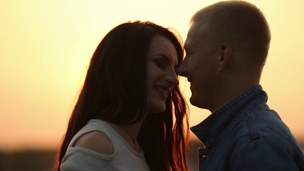 Piękna para szuka siebie twarzą w twarz i Całowanie o zachodzie słońca. - Materiał filmowy, wideo