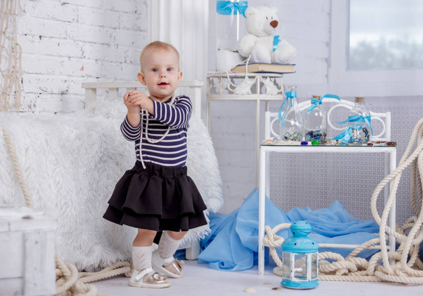 Portrait of a cute and naughty european little girl in a sailors clothing in the studio of marine style on a background of white brick wall - Foto, immagini