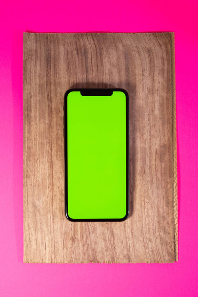 Luxury smartphone on iridescent fuchsia color with green chroma key display copy space to insert your content - Photo, Image