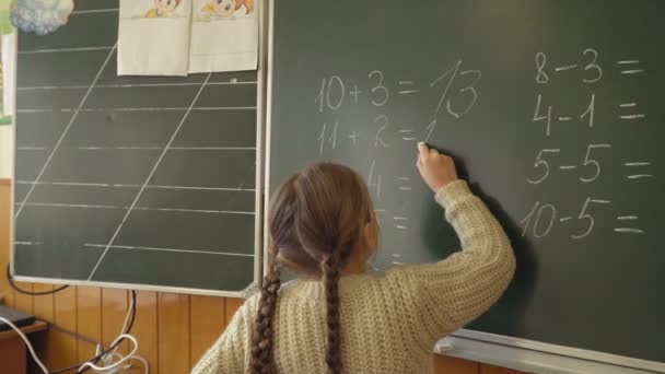 little girl near the board decides the calculations - Filmati, video