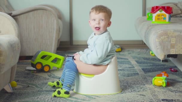 Adorable boy with a smartphone during potty training on the room. - Video