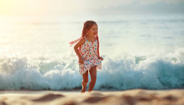 boldog gyermek lány repülő haj tánc és rúnaírásos a strandon található sunse - Fotó, kép