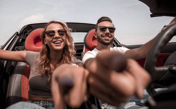 close up.young couple sitting in a convertible and pointing at you. - Fotoğraf, Görsel