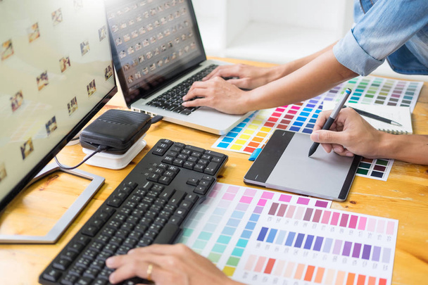 grafisch ontwerper team dat werkt op webdesign met behulp van kleurstalen illustratie met behulp van Tablet PC- en een stylus op bureaus In drukke creatieve Office bewerken - Foto, afbeelding