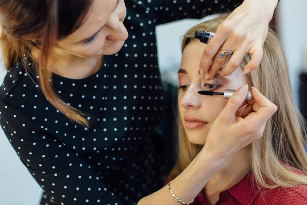 Make-up artist working in studio with young beautiful woman. - Фото, зображення