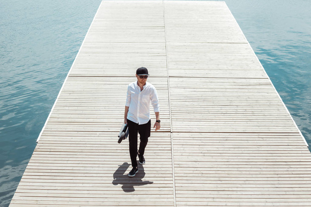 Photo of modern man with electric scooter at a wooden pier - Fotografie, Obrázek