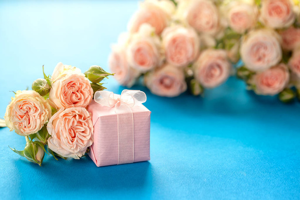 Pink gift or present box and Roses flowers on Blue background. Mothers Day, Birthday, Valentines Day, Womens Day, celebration concept. Space for text. - Foto, imagen