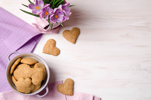 lilac crocuses and sesame dry cookies in the form of heart on a light wooden table - Fotoğraf, Görsel