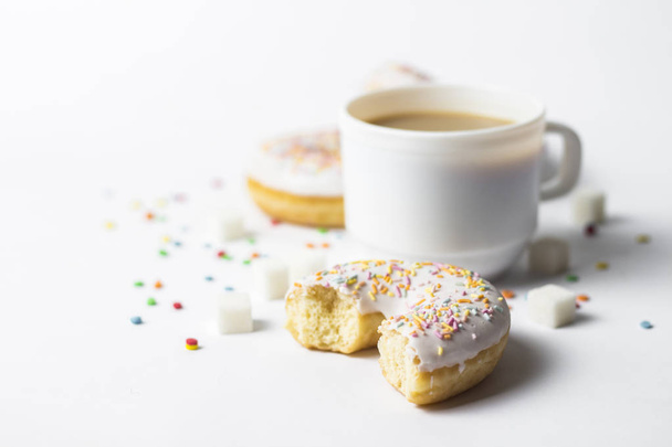 White Cup, coffee or tea with milk and fresh tasty donuts, sweet multicolored decorative candy on a white background. Bakery concept, fresh pastries, delicious breakfast, fast food - Foto, imagen