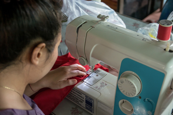 Женщина-швея, работающая на швейной машинке
.  - Фото, изображение