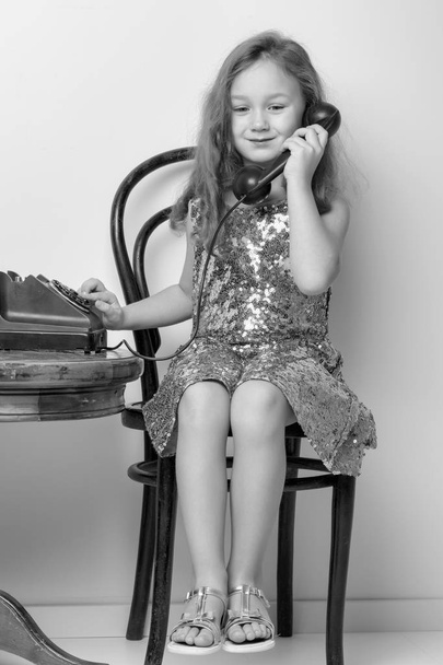 A little girl is ringing on the old phone. - Φωτογραφία, εικόνα