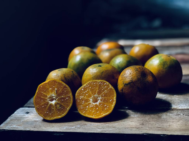 Fresh Orange on empty old wood plank,with space for your text design.Rustic still life and dark background, dimly light. Selective focus. - Foto, Imagen