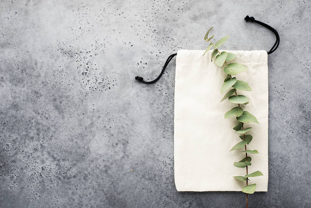 Eucalyptus branch on eco cotton bag for shopping and for items on a light background. Top view. Copy space - Foto, imagen