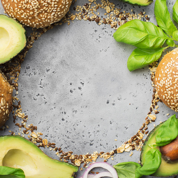 Ingredients for making healthy vegetarian avocado burger with basil, red onion, avocado on cereal buns. Gray light background. Top view, space. - Foto, afbeelding