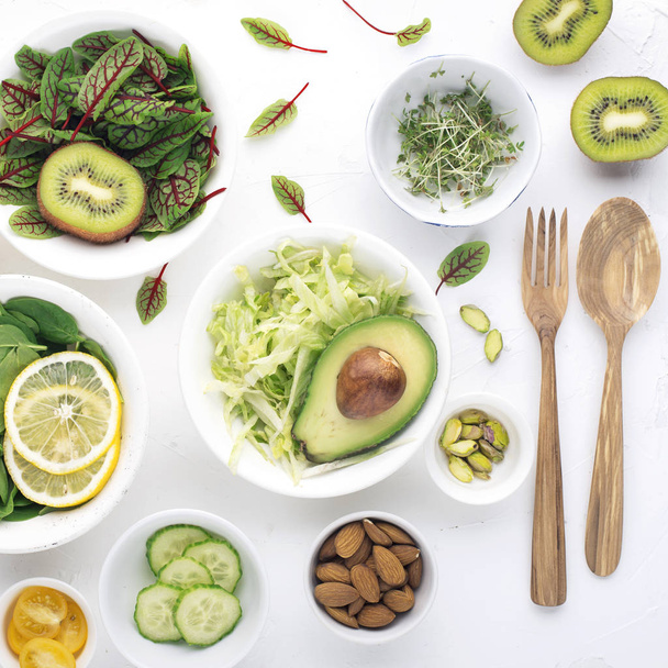 Green ingredients for spring detox salads: spinach, sorrel with red veins, cucumbers, radishes, iceberg lettuce, green peas, avocados, lemon, microgreen, yellow tomatoes on a white background with - Photo, image