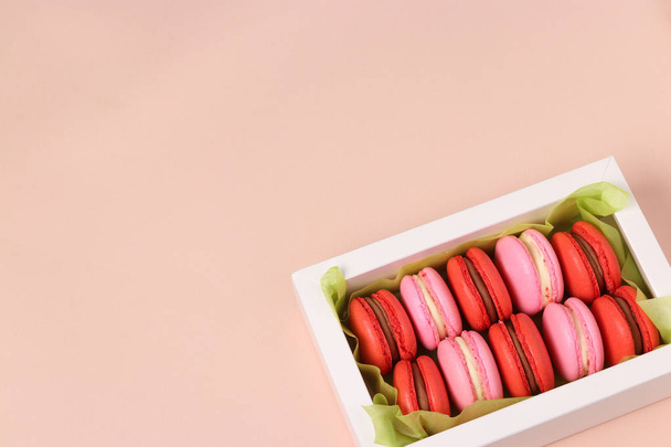 leckere süße Cookies Macaron, Makronen in einer weißen Geschenkbox auf rosa Hintergrund, rote und rosa Macarons. Kopierraum - Foto, Bild