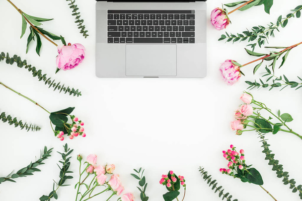 白い背景の上のノート パソコンとピンクの花と花のフレーム。平面図です。フラットを置く. - 写真・画像